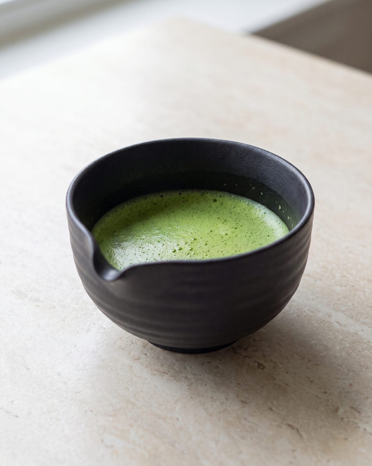 In use: Ceramic Matcha Bowl with Spout – Black, filled with freshly whisked matcha