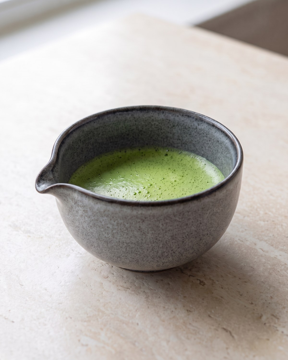 In use: Ceramic Matcha Bowl with Spout – Stone Grey, filled with freshly whisked matcha