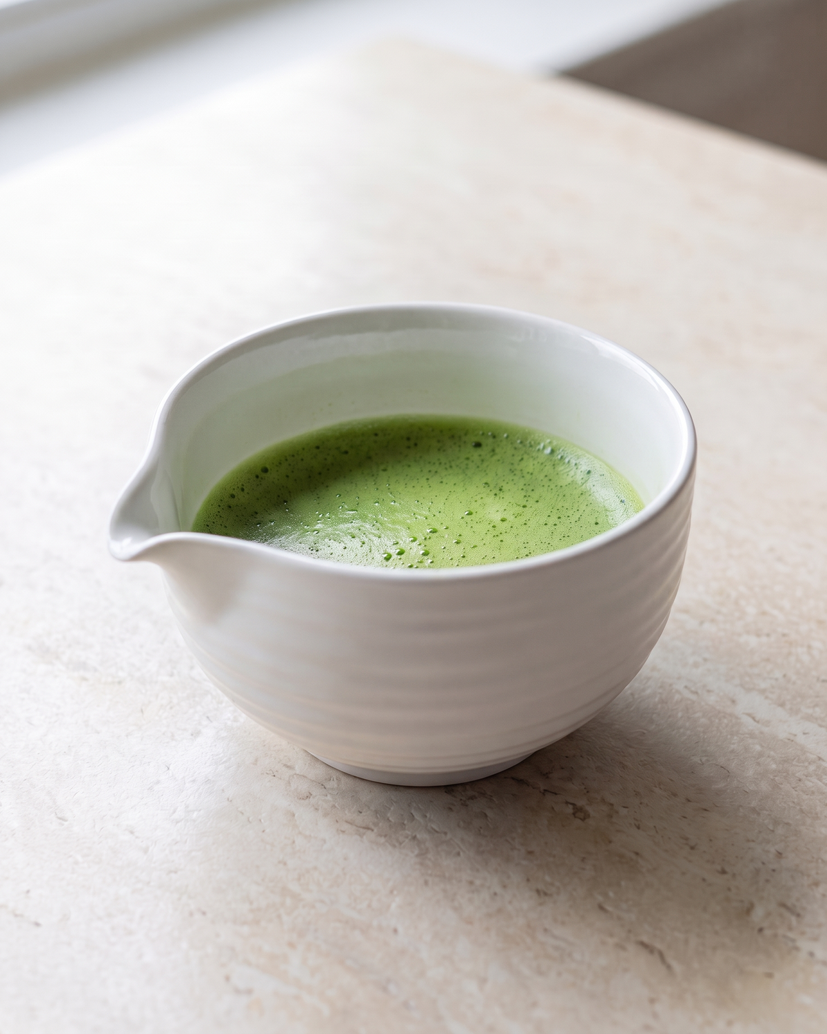 In use: Ceramic Matcha Bowl with Spout – White, filled with freshly whisked matcha