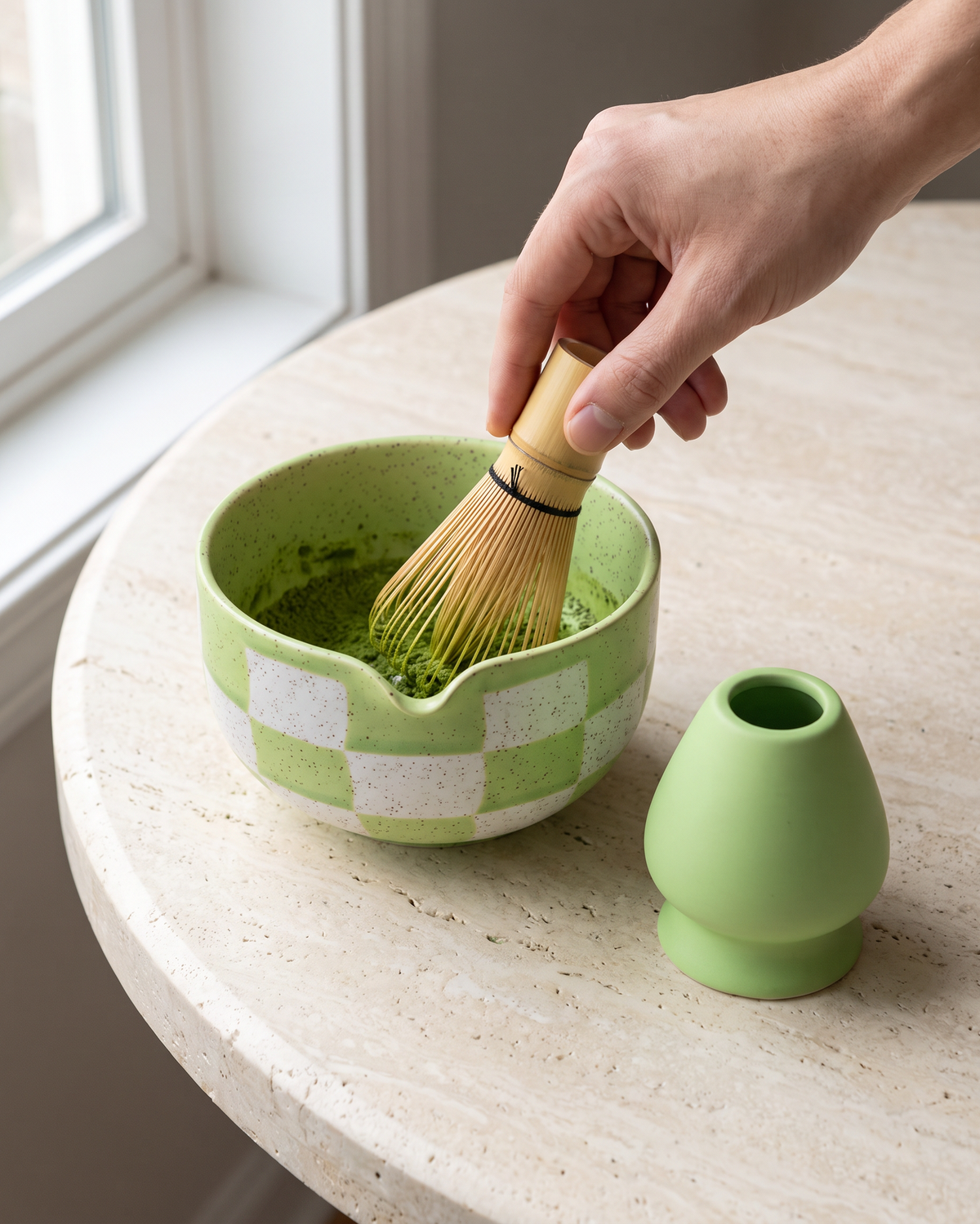 In use: 2-Piece Checkerboard Bowl & Holder Set – Green, hand whisking matcha in the bowl with a bamboo whisk (sold separately), holder beside