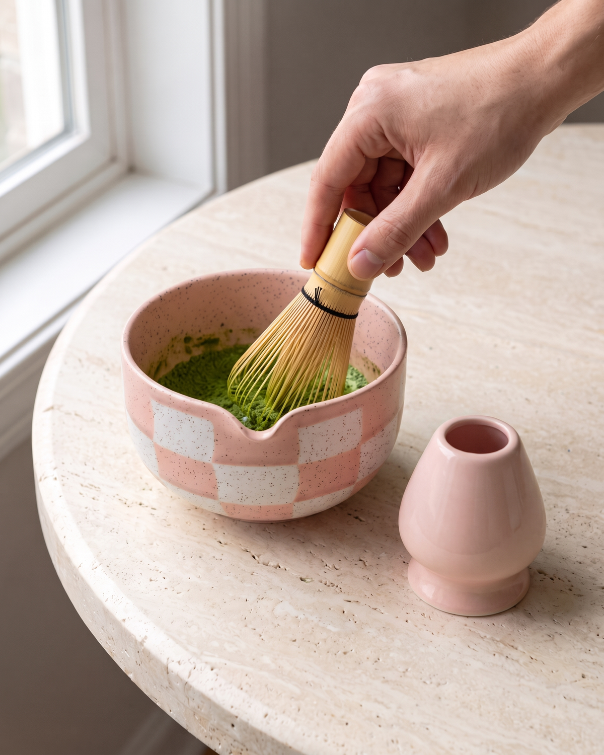 In use: 2-Piece Checkerboard Bowl & Holder Set – Pink, hand whisking matcha in the bowl with a bamboo whisk (sold separately), holder beside