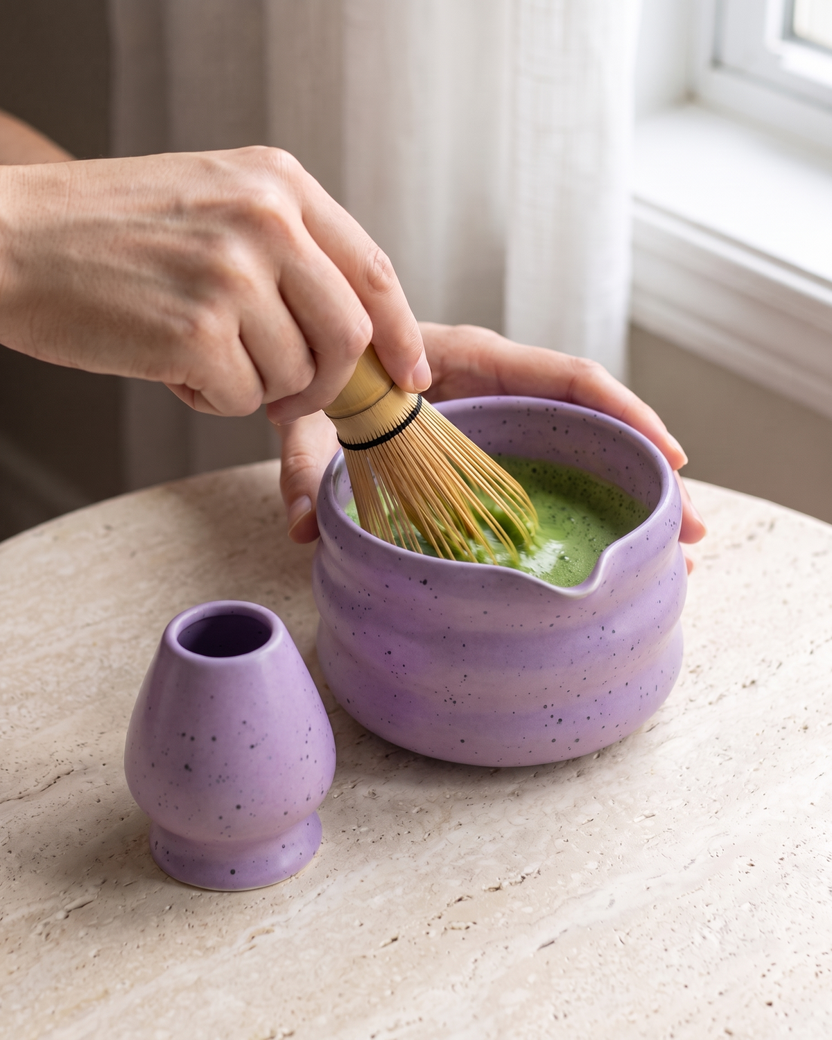 In use: 2-Piece Speckled Matcha Bowl & Holder Set – Purple, hand whisking matcha in the bowl with a bamboo whisk (sold separately), holder beside