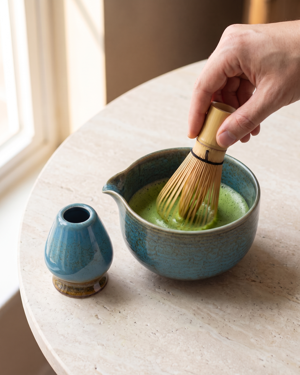 In use: 2-Piece Glazed Bowl & Holder Set – Lagoon Blue, hand whisking matcha in the bowl with a bamboo whisk (sold separately), holder beside
