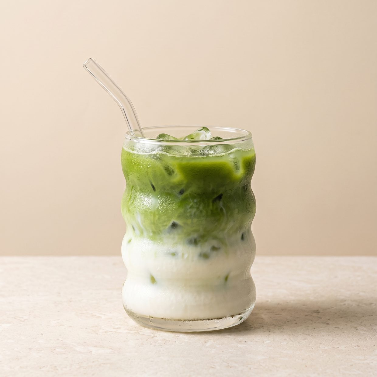 Iced matcha latte layered over milk in a ripple glass