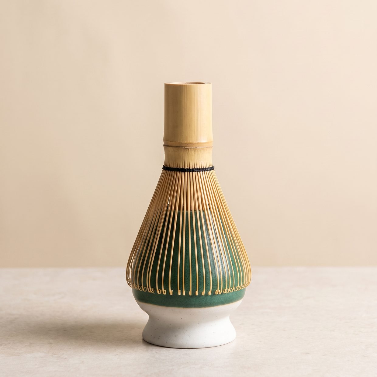 Bamboo whisk drying prong-side down on a green ceramic holder